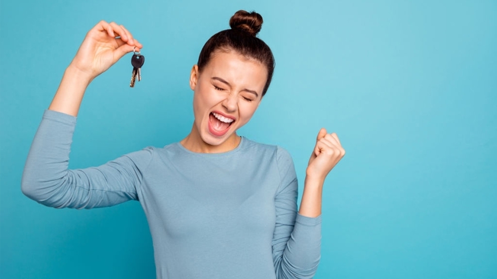 A happy lady holding house key happily with close eyes