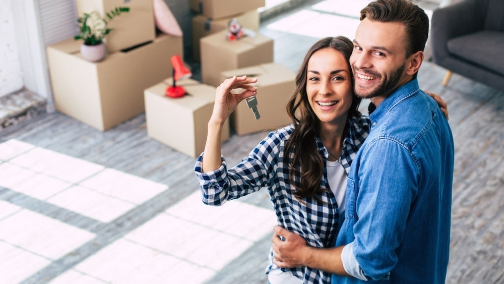 A young couple holds happily a key of their new home