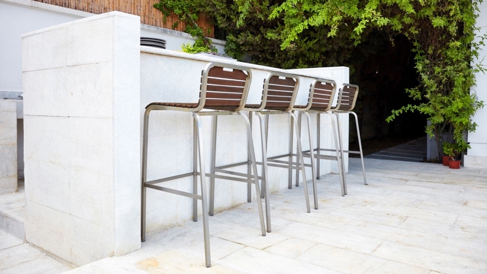 An outdoor bar with four empty bar stool chairs