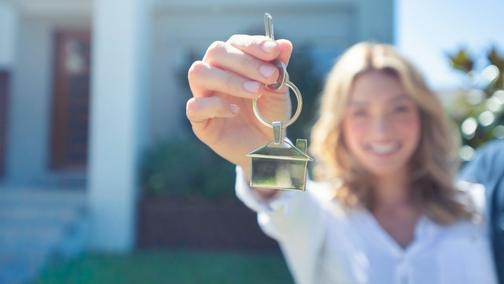 Young woman holding the key to her new house