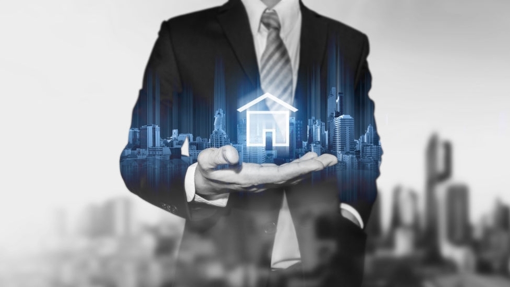 A businessman holding modern buildings hologram and home icon real estate business