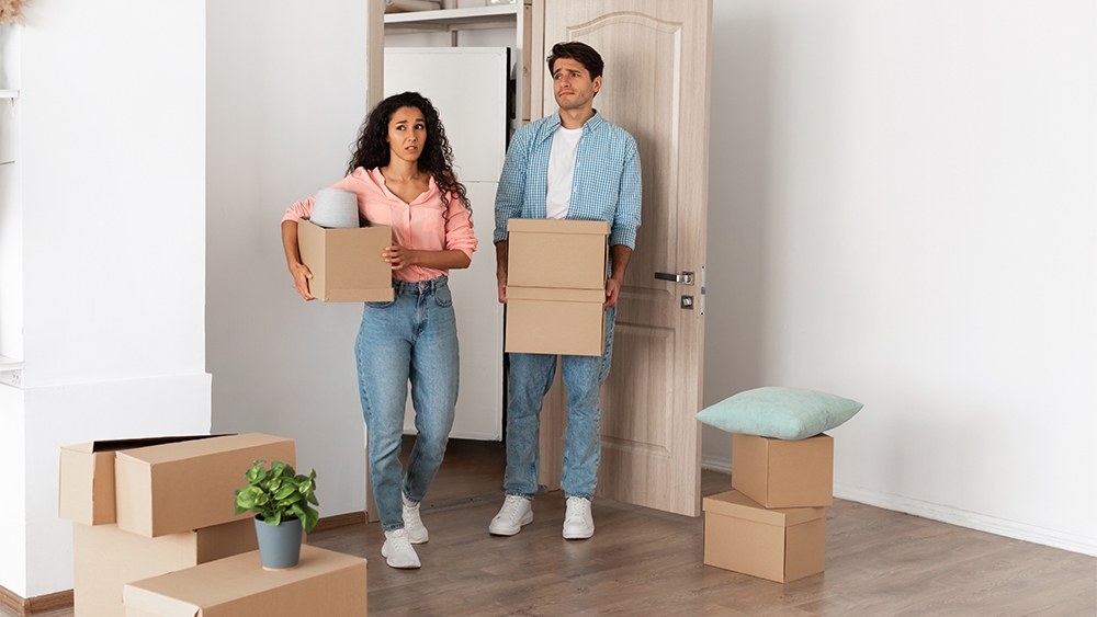 Unhappy couple holding cardboard boxes walking