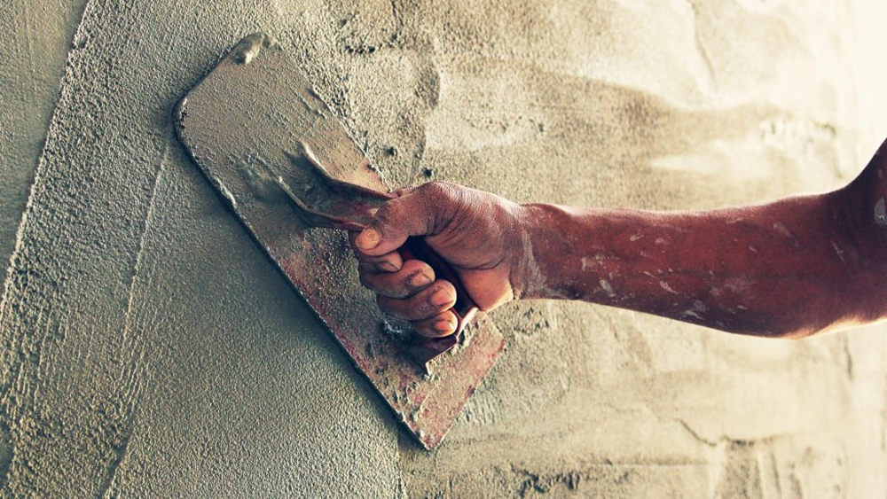 Construction worker plastering cement on wall