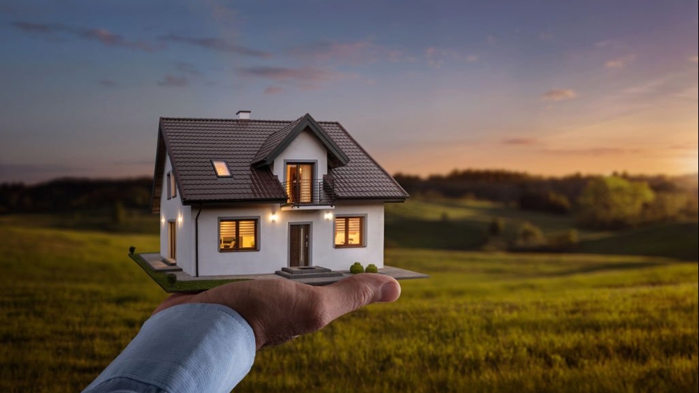 Male hand showing a new dream house at the empty field