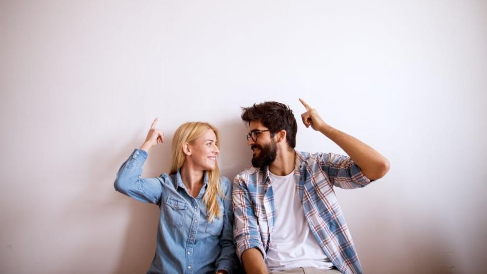 Happy couple standing against wall