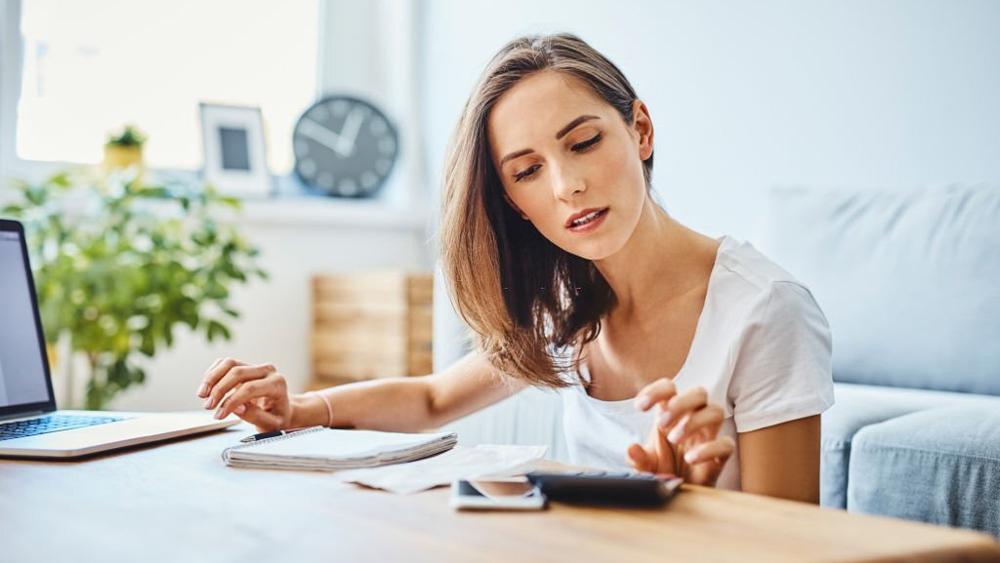 Woman preparing home budget using laptop calculator