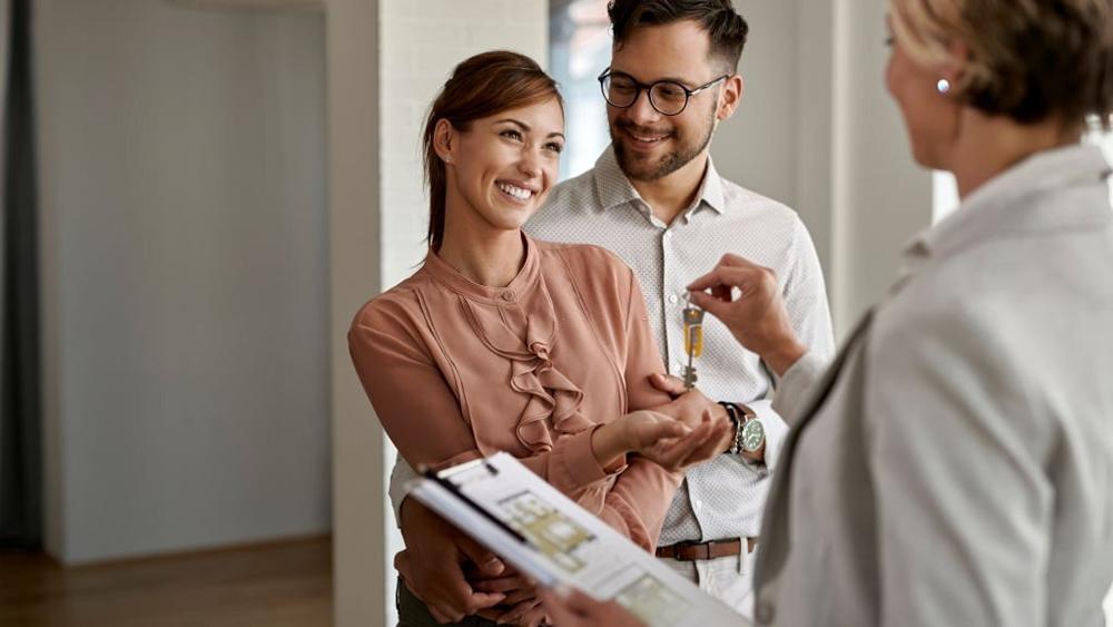 Happy couple receiving keys of their new-home from real estate agent