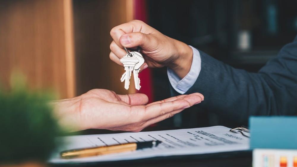 Estate agent giving house keys after signing agreement