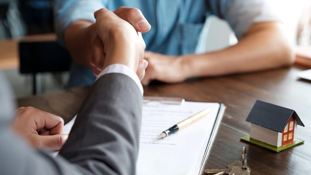 Estate agent shaking hands with his customer after contract signature