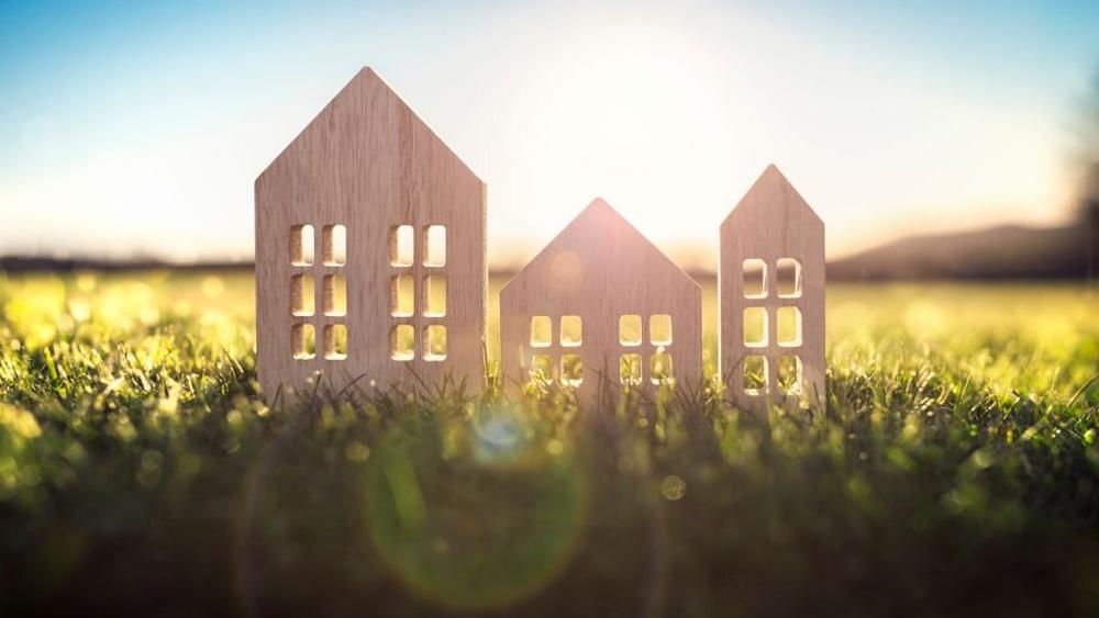 Ecological wood model house in empty field at sunset