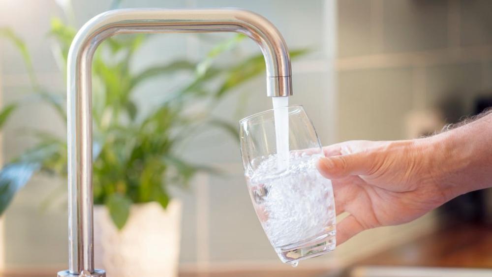 Filling up a glass with drinking water from kitchen tap