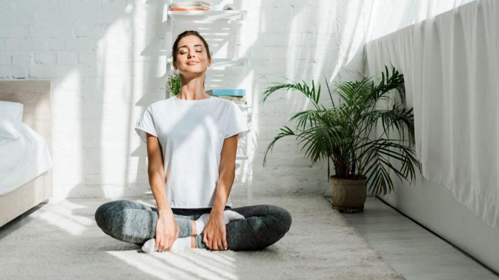 Happy girl practicing yoga in bedroom