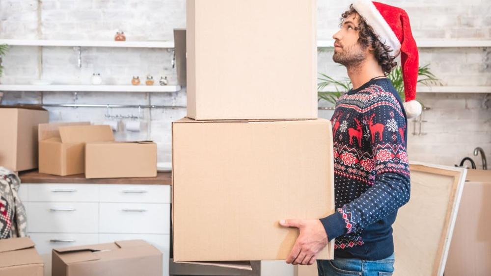 Man in Santa hat holding cardboard boxes during relocation