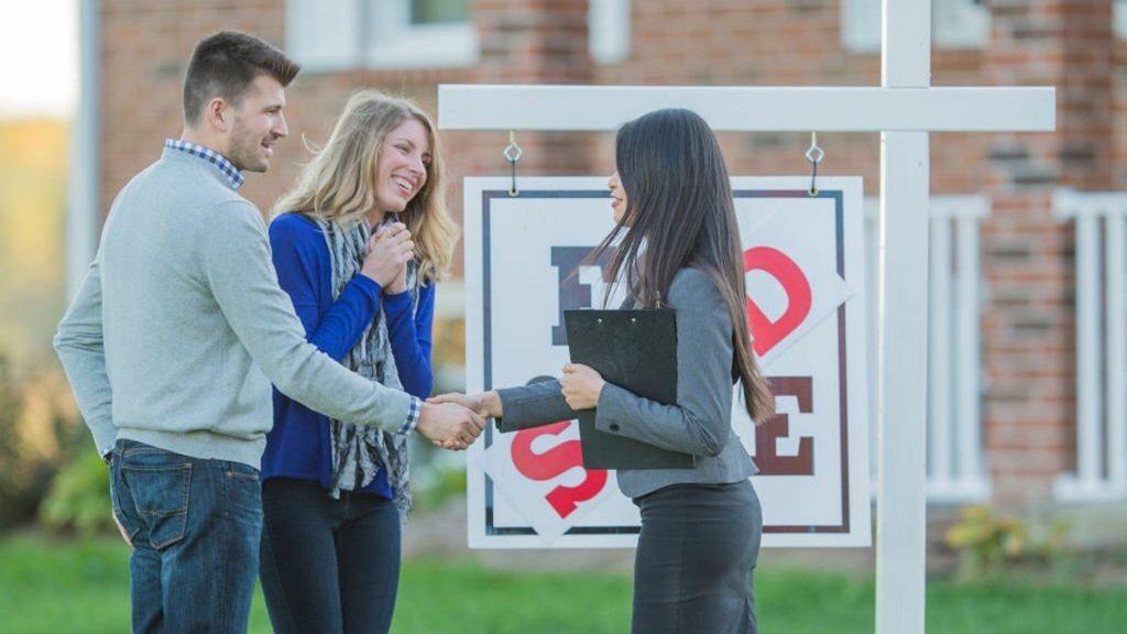 Excited couple shakes hands with a real estate agent