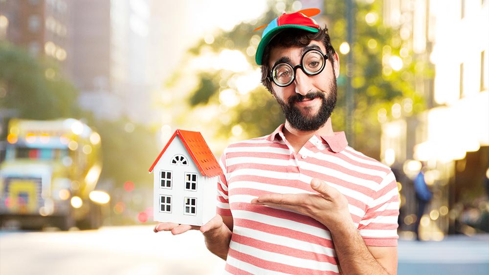 Man with happy expression holding house maquette