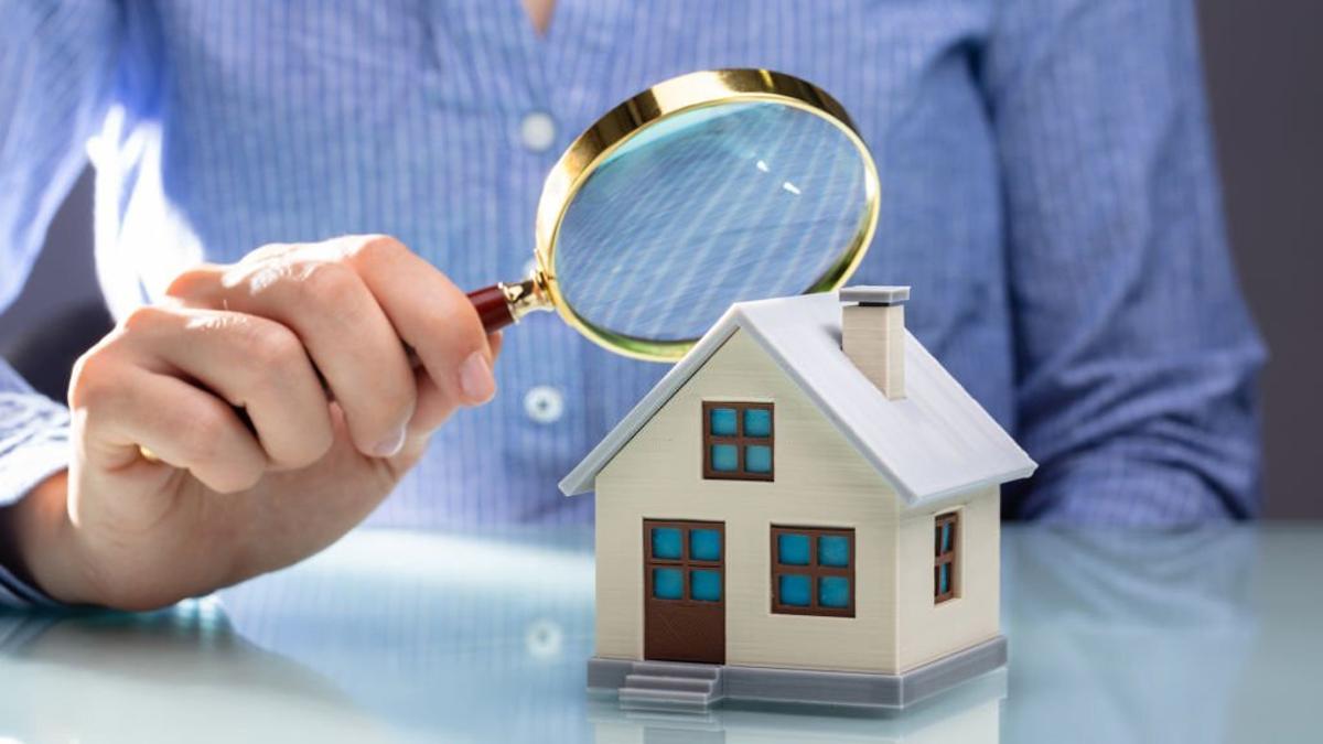 Businesswoman holding magnifying glass over house model