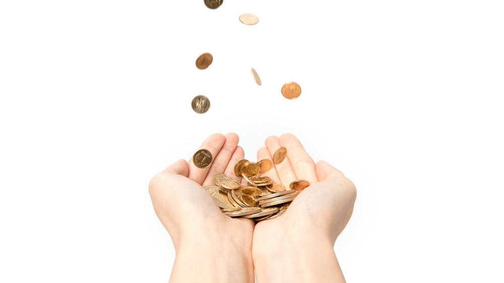 Various coins falling into a person's hands