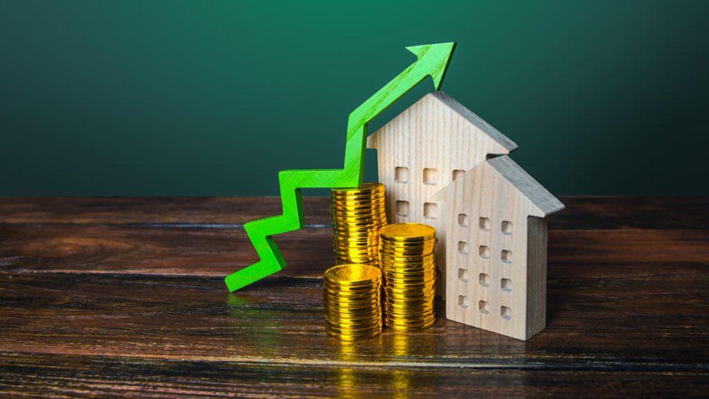 Green arrow up over wooden houses showing increasing cost