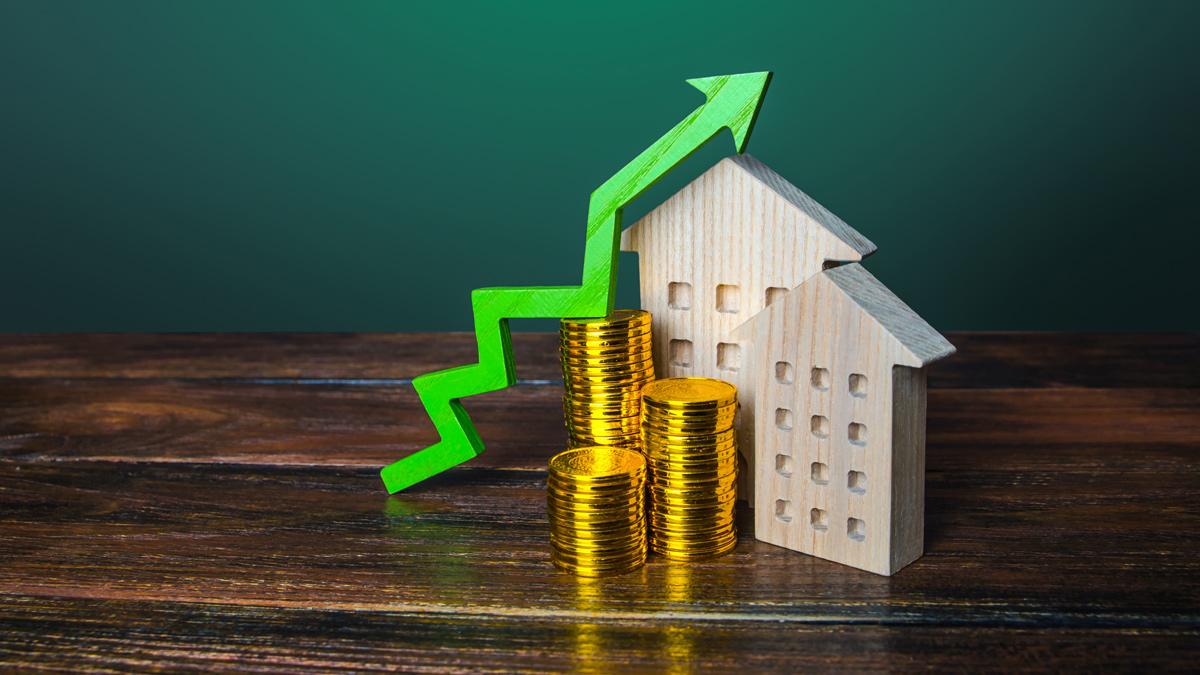 Green arrow up over wooden houses showing increasing cost