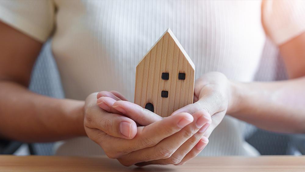 Hand holding wood home model