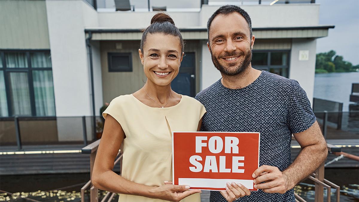 Lovely couple keeping for sale sign for selling their home