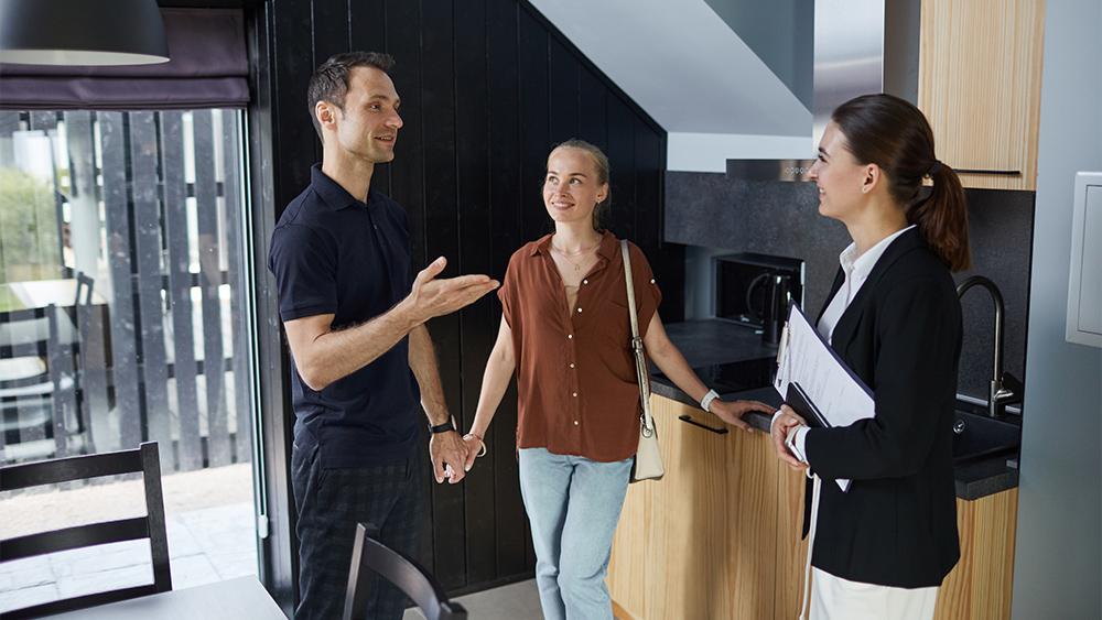 Happy couple in house tour with real estate agent