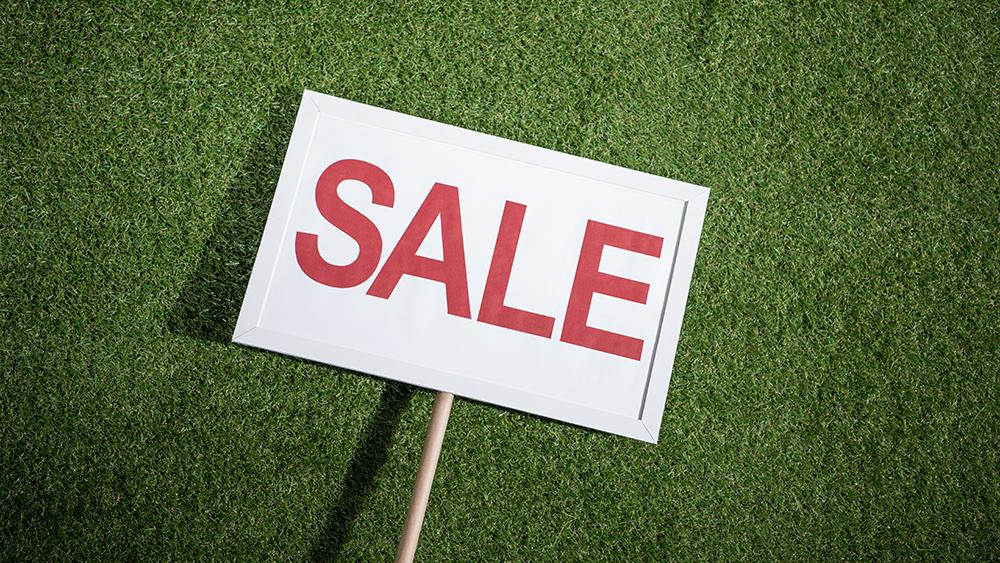 White sale banner lying on green grass going to be used for a house for sale