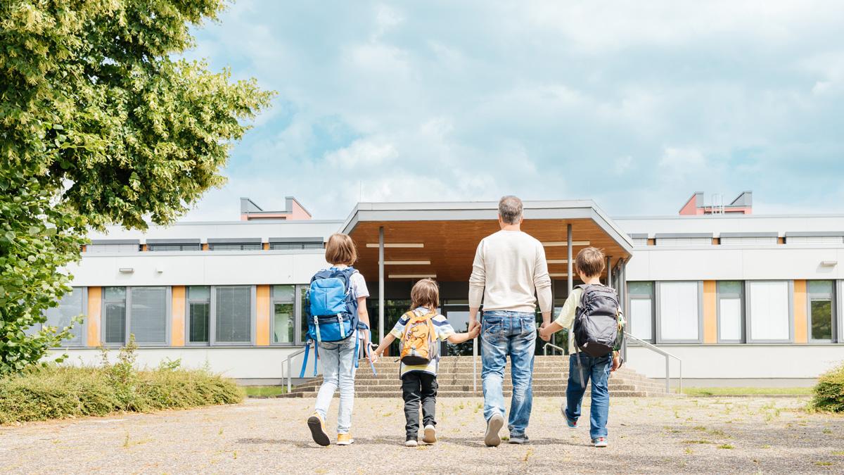 Happy parent takes his children to school