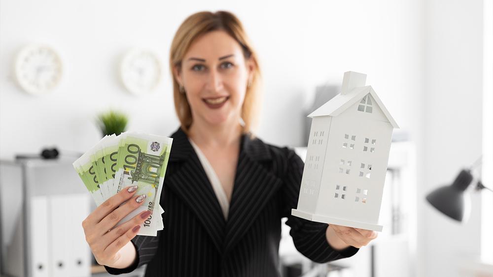 A young girl standing in office and holding cash money for buying a home