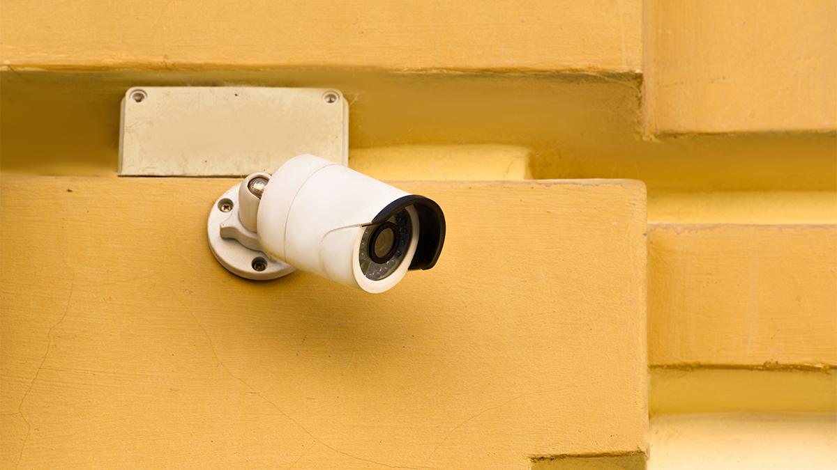 Closeup view of security camera on yellow building