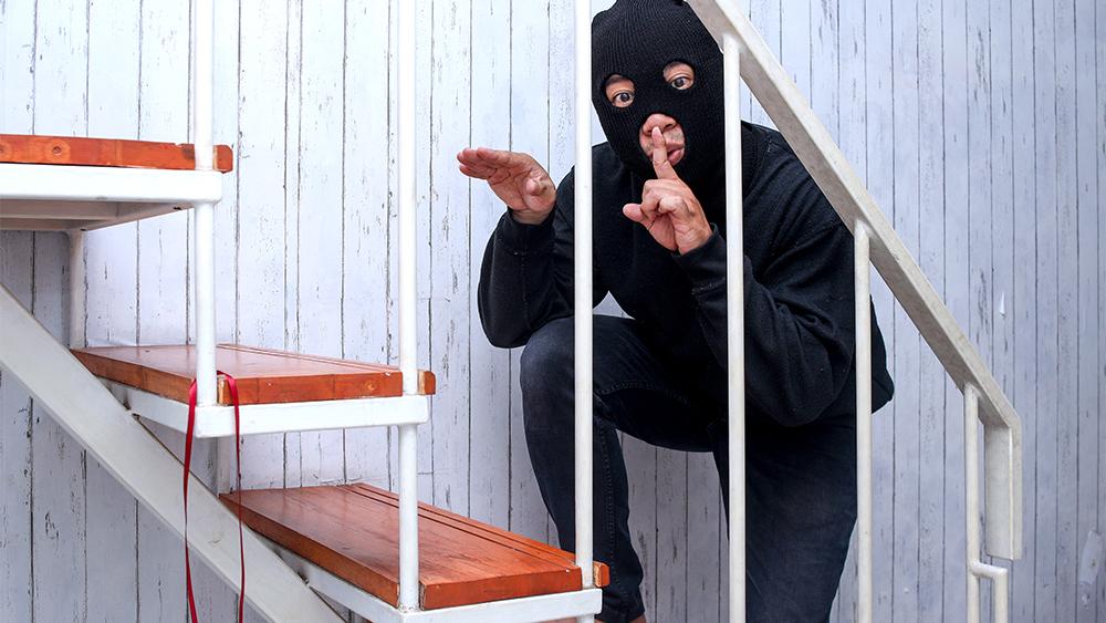 Hided masked thief standing on stairs