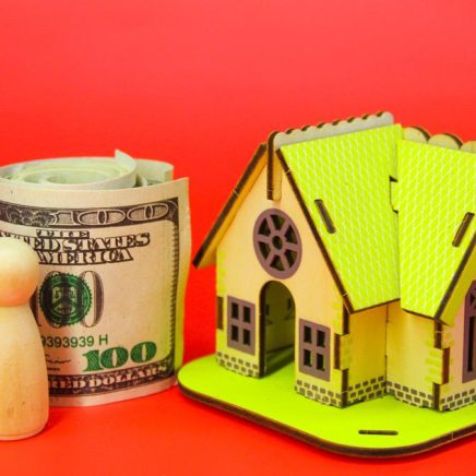 Two wooden figures with paper money and a house Two wooden figures with paper money and a house